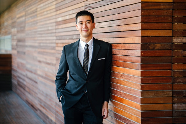 man in suit leaning against a wall